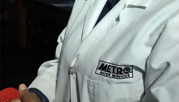 Person wearing lab coat with Metro Water Services logo