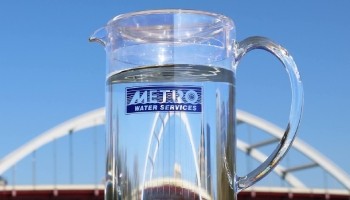 pitcher of water with Metro Water Services logo in front of bridge
