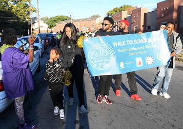 group of people walking down a street holding a banner