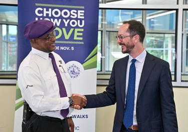 Mayor Freddie O'Connell shakes hands in front of a Choose How You Move sign