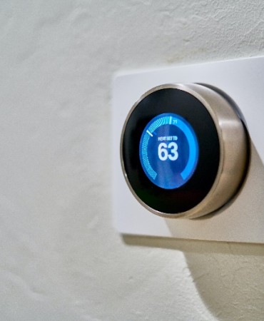 Smart thermostat on wall set at 63 degrees