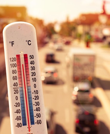 thermometer showing hot temperatures in front of city street