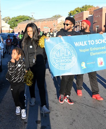 group of people walking down a street holding a banner