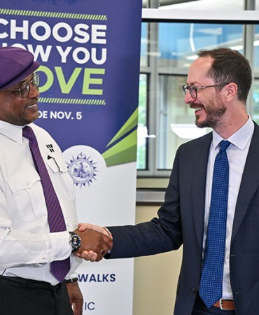 Mayor Freddie O'Connell shakes hands in front of a Choose How You Move sign