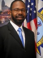 Man in a suit standing next to flags